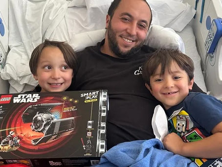 a man with two children laying in a hospital bed