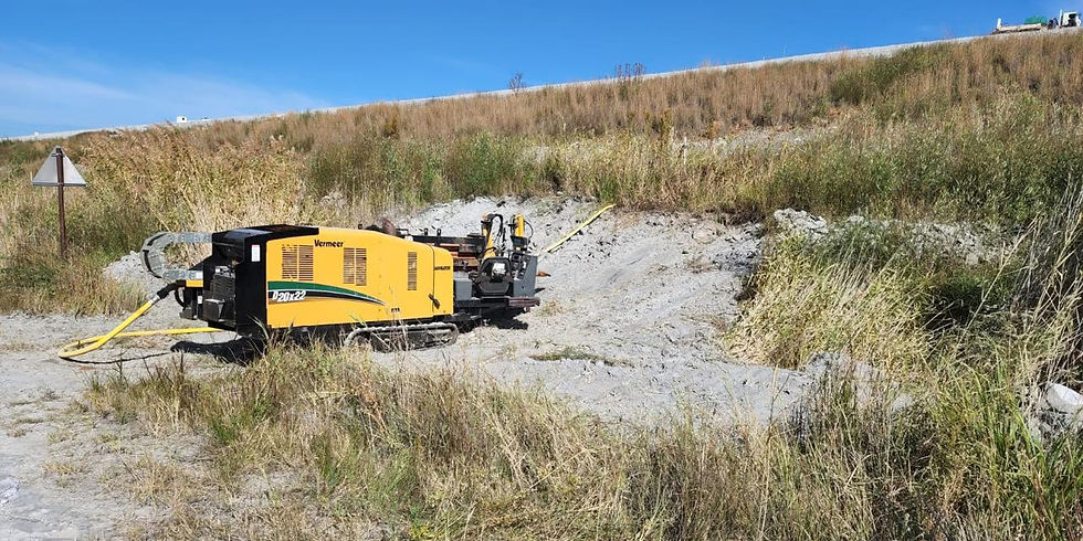 Vermeer horizontal directional drilling rig set up on a sandy construction site with grass embankments and clear blue sky.