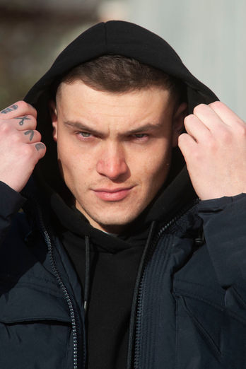 Street photography/ Man with hood looks directly into the camera