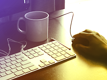 Man's hand at computer with coffee mug