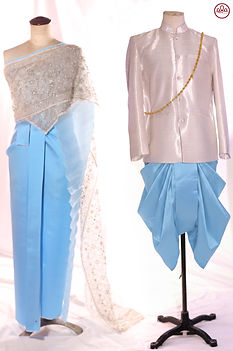 Thai wedding couple set displayed on mannequins featuring a sky-blue silk skirt with white embellished shawl for the bride and a white silk suit with sky-blue traditional chong kraben for the groom, styled in a modern Thai ceremonial design.