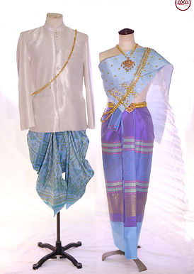 Matching blue Thai silk outfit with gold-thread details – men’s white jacket and women’s light-blue draped shoulder cloth embroidered with gold thread and green jewel wing design – traditional Thai costume rental by Pinder Atelier.