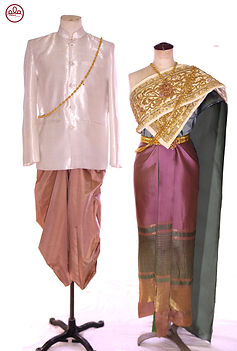 Thai traditional couple outfit – bride in purple nude silk with green accents and gold embroidery, draped with white sabai; groom in green silk ensemble with gold details – elegant Thai wedding attire