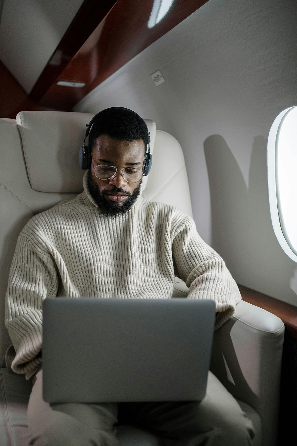 Man working on his laptop while seated on an airplane.