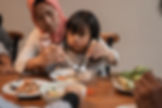 muslim mom eat with her daughter sitting lap