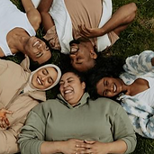 Friends smiling and lying on the grass in a circle