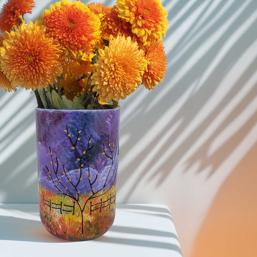 Vibrant bouquet of orange and yellow chrysanthemums in a cylindrical vase made from recycled bottles, hand-painted with a fal