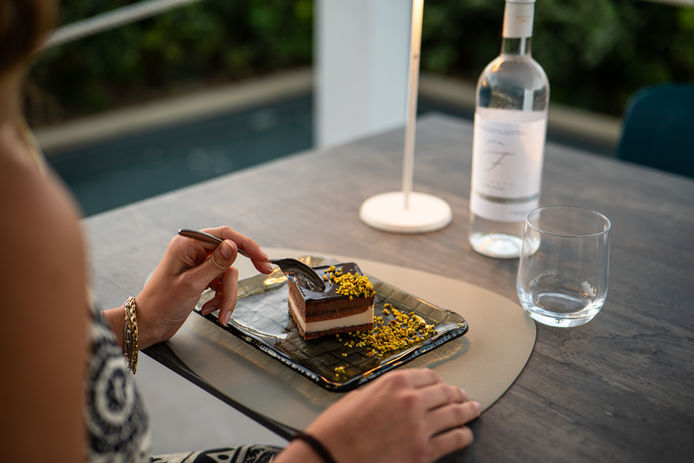 Persona mangia torta di cioccolato, bottiglia di vino e vetro, Ville di lusso con piscina in Sicilia.