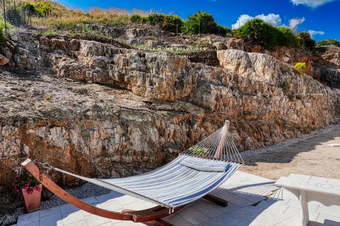 Amaca rilassante su patio, con imponente parete rocciosa sullo sfondo.