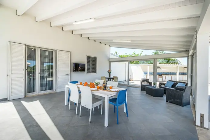 Splendida veranda coperta con tavolo da pranzo apparecchiato e comoda zona lounge.