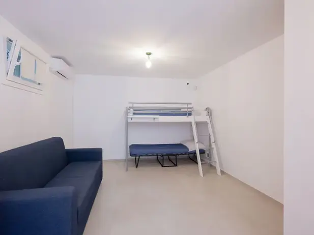 Camera bianca, divano blu, letto a castello per case vacanze Castellammare.