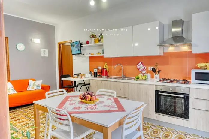 Cucina moderna e sala da pranzo con accenti arancioni vivaci e pavimenti decorati.