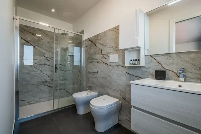 Bagno moderno con doccia in vetro, servizi igienici e lavabo elegante.