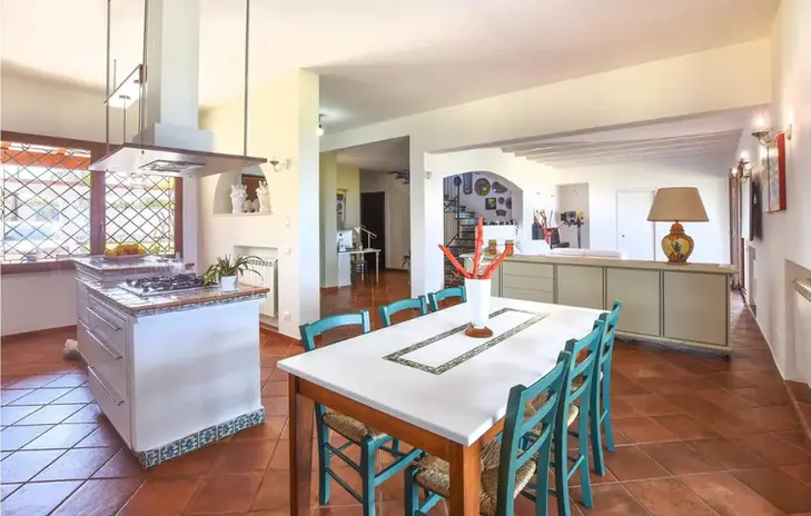 Cucina moderna open space con isola, tavolo da pranzo e sedie.