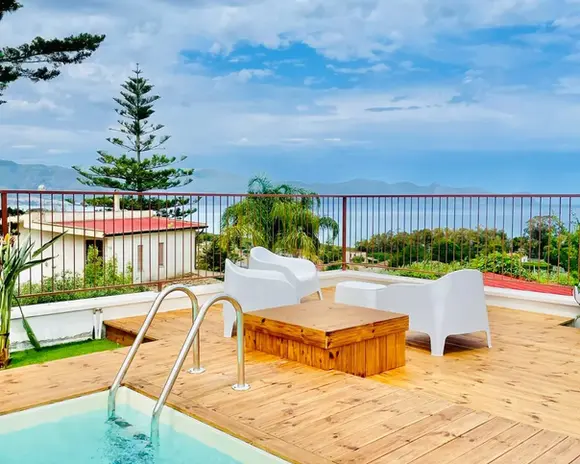 Elegante terrazza con piscina, mobili moderni e vista mare in Sicilia.