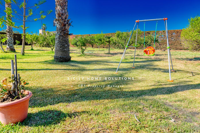 Un parco giochi con altalena e alberi, Sicily Stone Solutions ville deluxe.