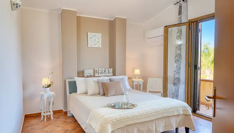 Camera da letto accogliente con letto matrimoniale, balcone aperto e decorazione "DREAM".