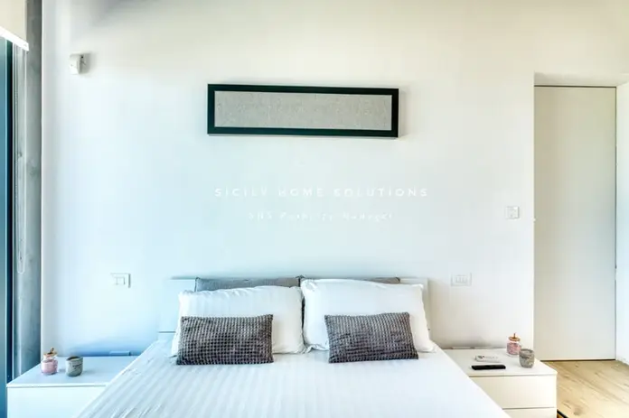 Moderna camera da letto bianca con letto matrimoniale e comodini minimalisti.