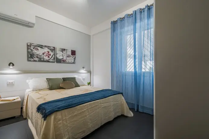 Camera moderna con letto matrimoniale, tende azzurre, aria condizionata.