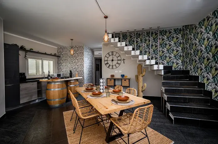 Sala da pranzo moderna con tavolo in legno, sedie in vimini e scale.