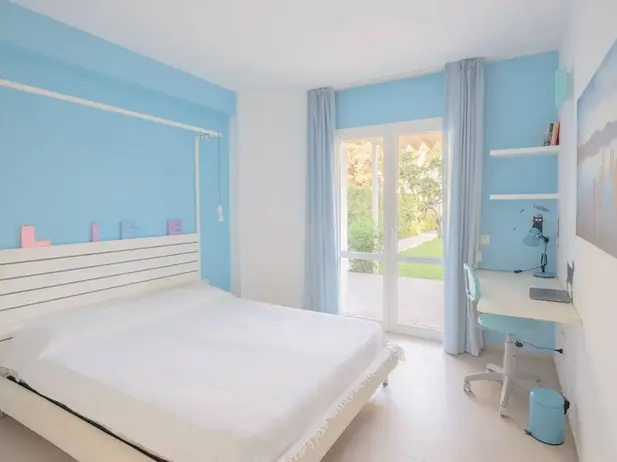 Camera da letto moderna azzurra, letto bianco, scrivania. Case vacanze Castellammare.