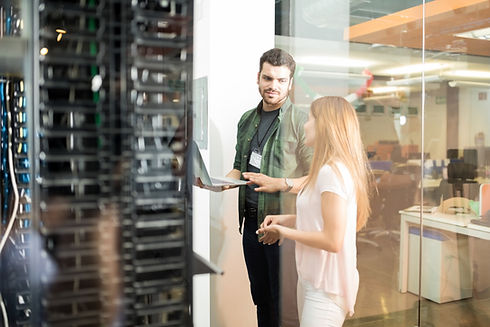 two-business-people-standing-server-room-with-laptop-discussing.jpg