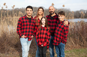 Family portrait: parents and three children in red plaid shirts