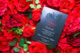 Valentina's Sweet 16 party invitation amidst red roses