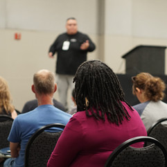 Massey Campos giving a speech as many people listen on during a homeschool convention