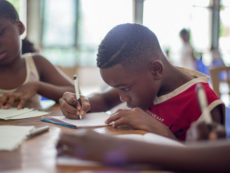 Two children writing together in a classroom, representing school support for pupils with SEND