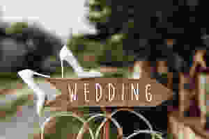 Wooden arrow reading "Wedding" on wood post pointing to direction of wedding