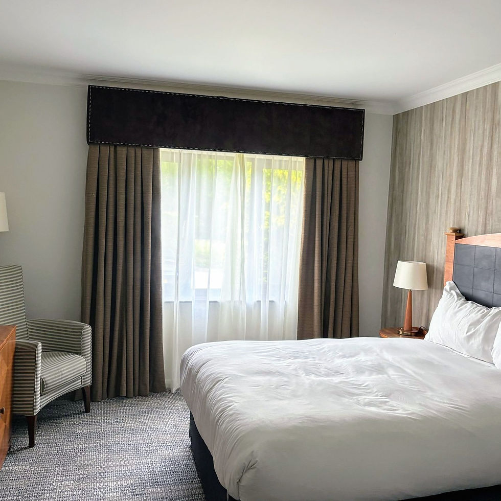 A hotel bedroom showing curtains and voiles hanging at the windows.