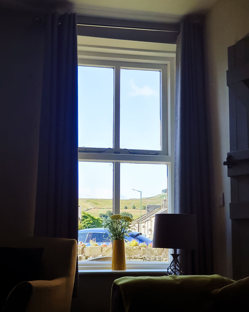 A window scene with curtains showing sunshine and green hills as a view.