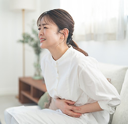 腹痛でお腹を押さえる女性