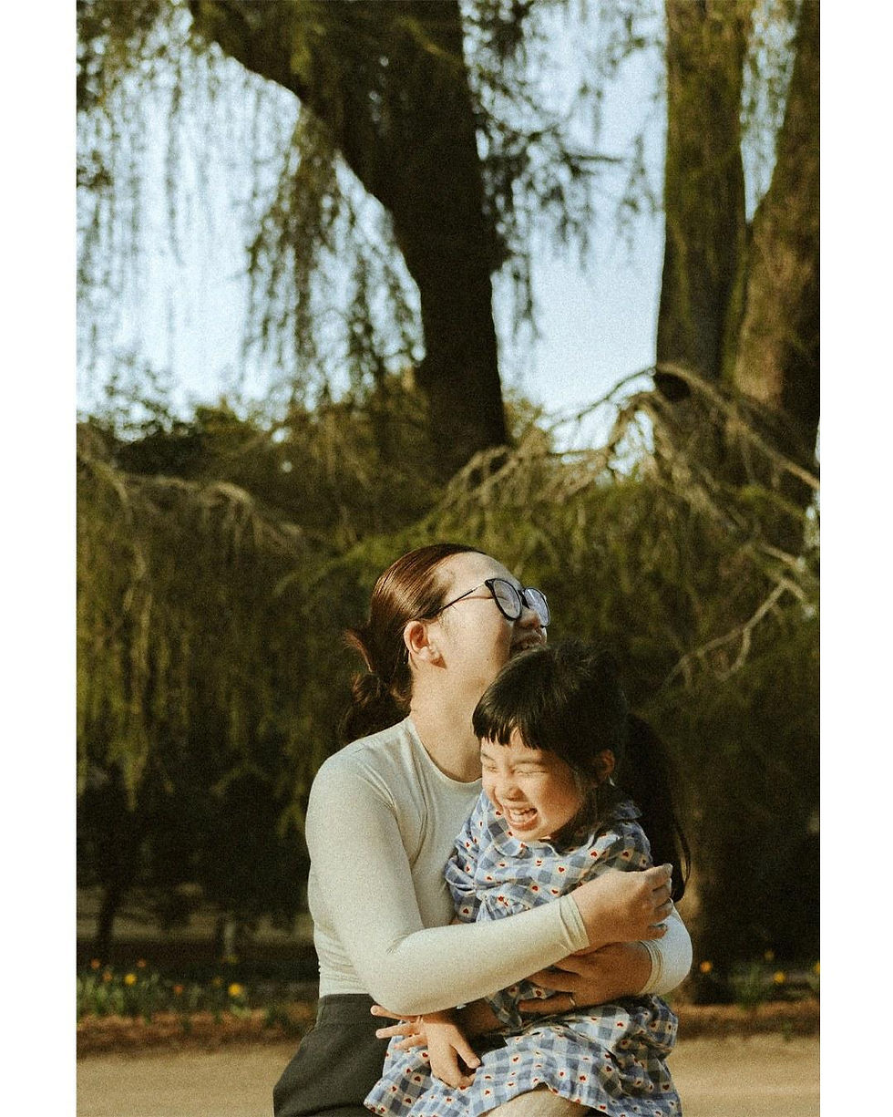 Mother hugging her laughing daughter beneath the cedars at Hopelands Gardens, Aiken SC family photography session