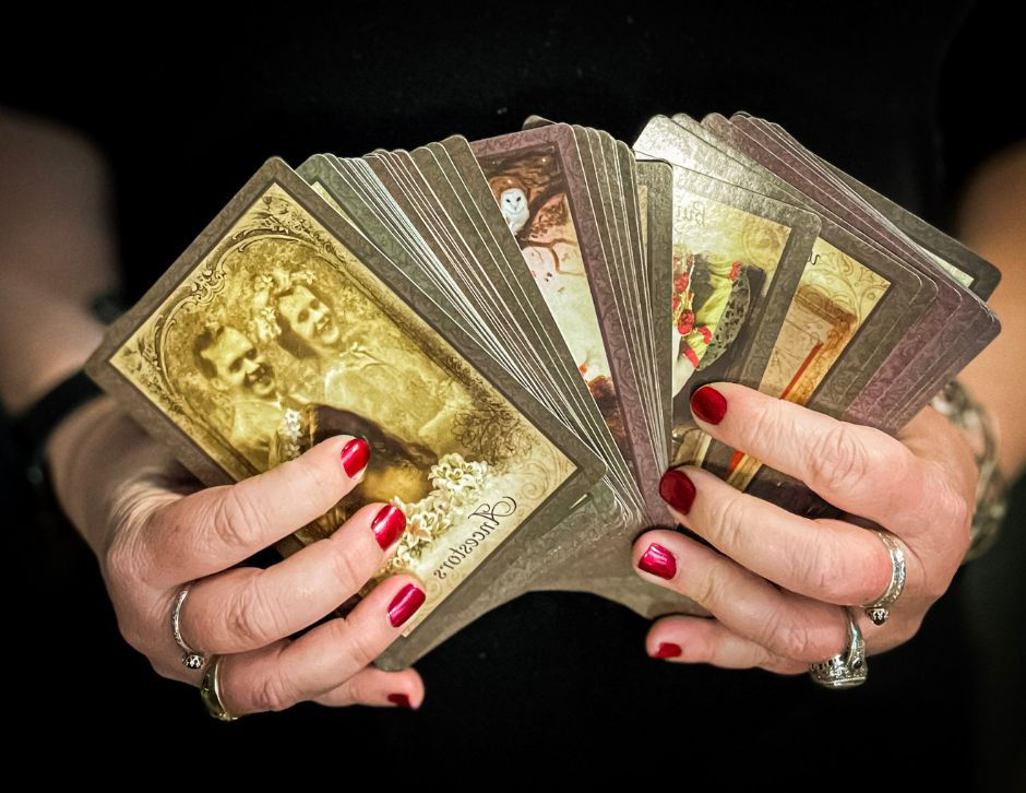The Vintage Oracle Deck speed out in hands with red nail polish