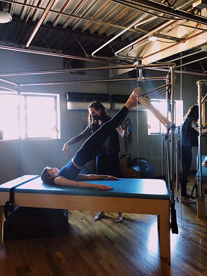 Pilates instructor cues client on apparatus