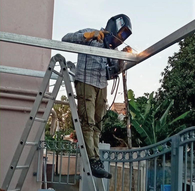 Yvan The Handyman welding main metal tube support for the carport