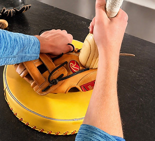 A baseball glove being broken in with a mallet