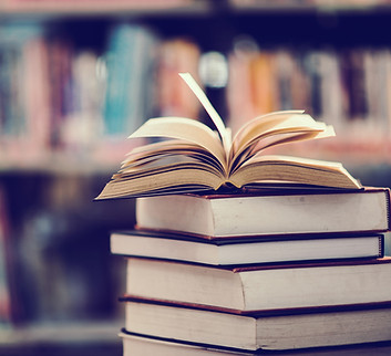 Pila de libros con una biblioteca de fondo