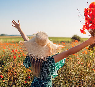 Young woman raised arms holding bouquet of poppies flowers walking in summer field. Happy
