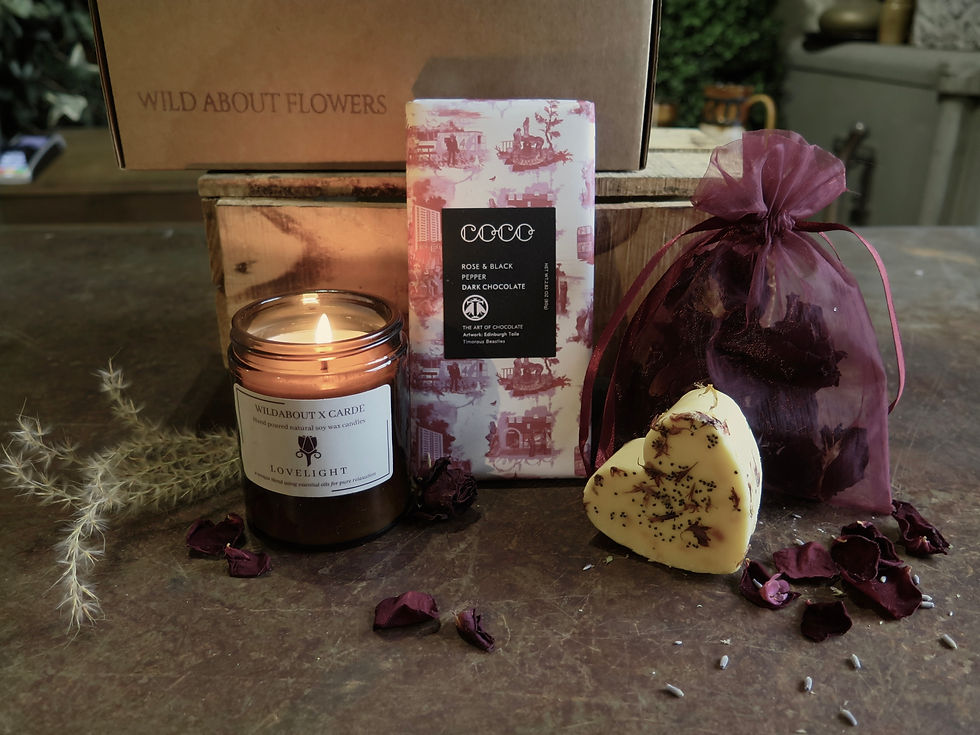 Warmly lit candle with heart shaped soap and chocolate bar