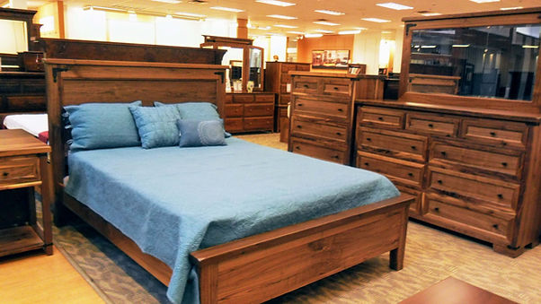 Farmhouse Bedroom Collection features queen panel bed, open nightstand with one drawer and shelf, tall mule dresser with 9 drawers and mirror, bureau chest with 6 drawers. All pieces are constructed of rustic walnut and feature black iron accents at the corners.