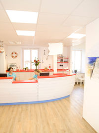 Heller Empfangsbereich mit nautischer Dekoration, rotem Bootstresen und Strandwandgemälde.