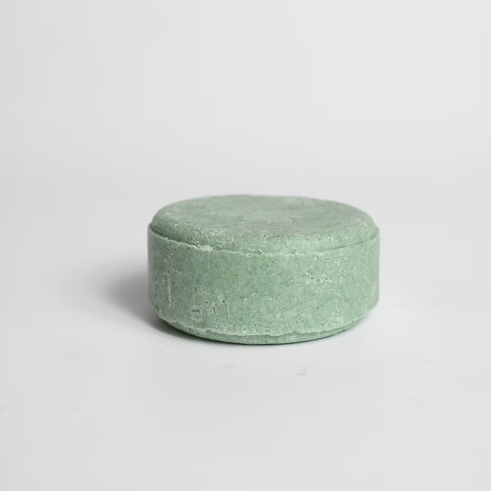 Shampoo sólido em formato redondo sobre um fundo branco, capturado de perto e sem embalagem.