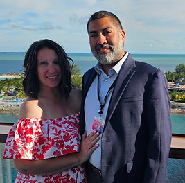 Couple standing on a cruise ship balcony overlooking a tropical port destination
