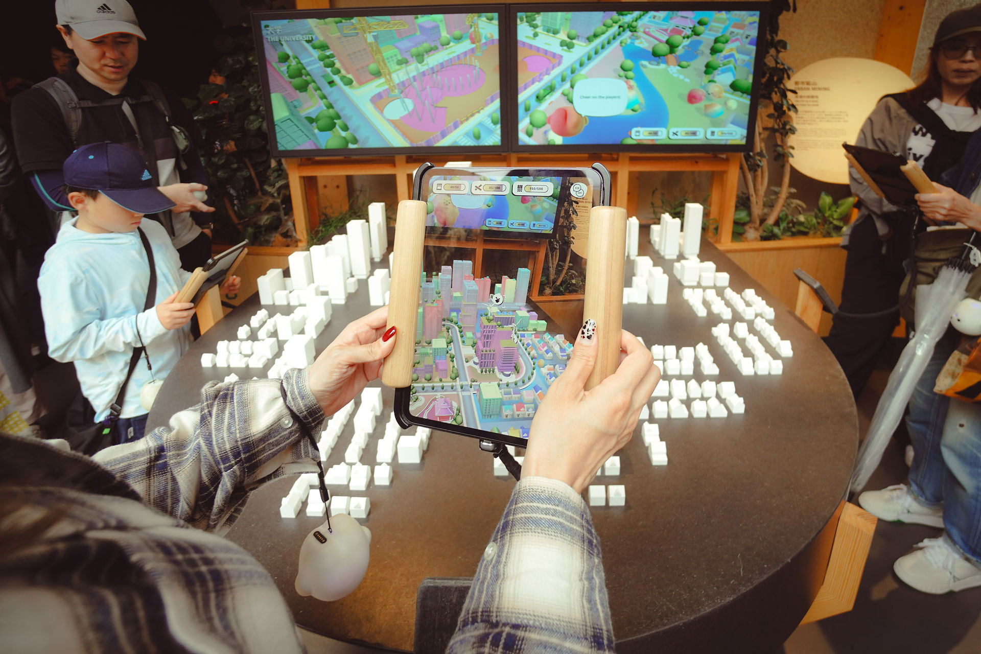 Visitor using a tablet to interact with an AR city model at the German Pavilion Expo 2025 Osaka