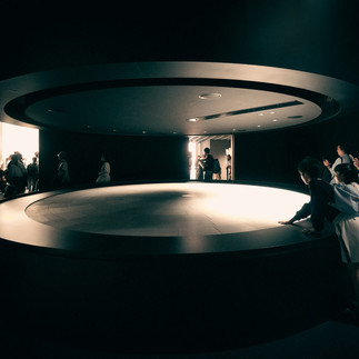 Visitors observing a circular light installation inside the Japan Pavilion showcasing sustainability storytelling