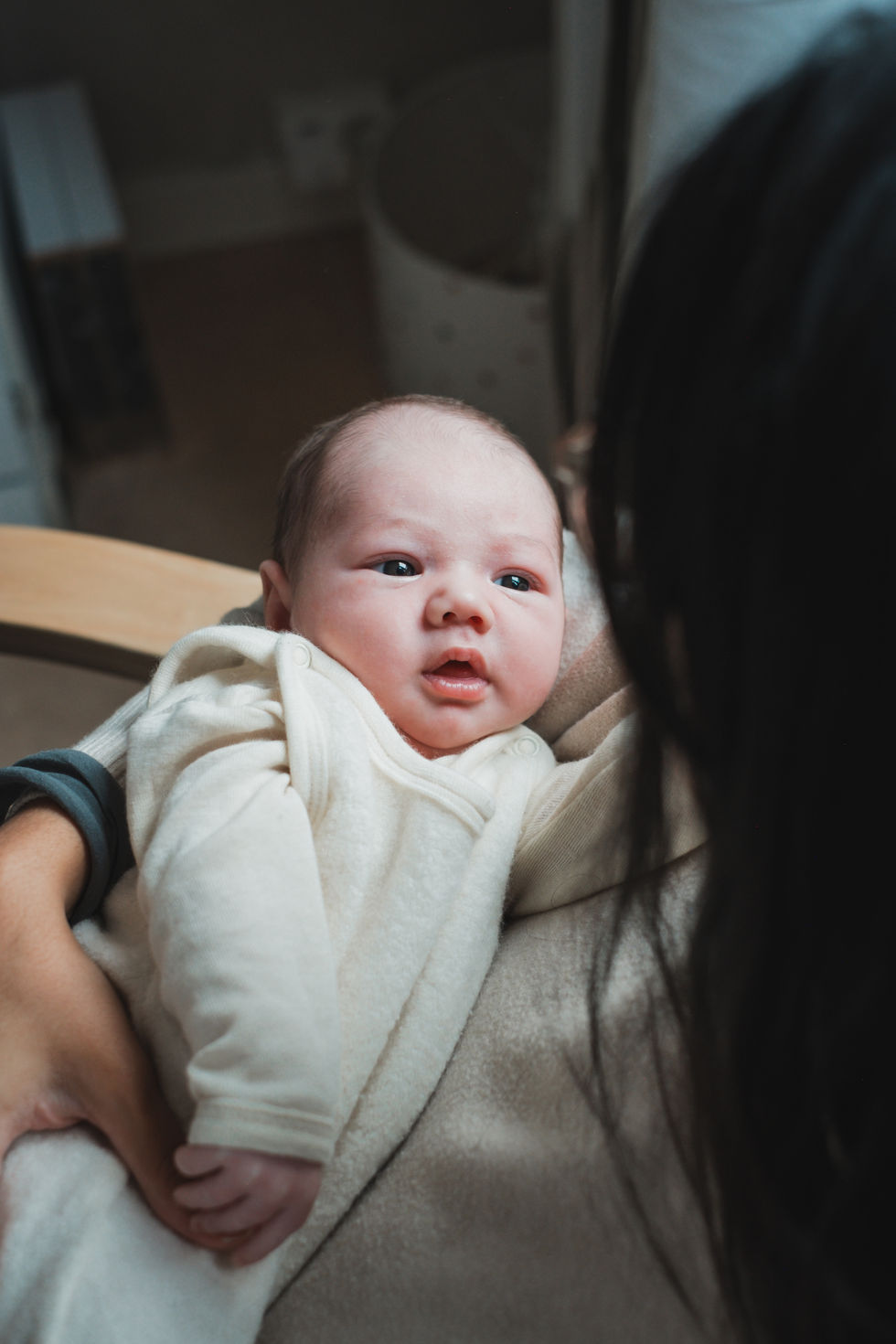 Baby mit Blick zur Kamera – persönliche Neugeborenenfotos bei euch zu Hause