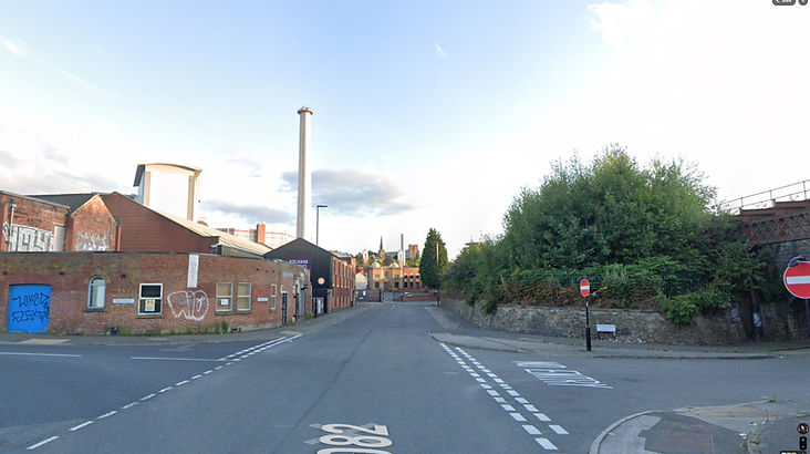Top Gear Series 15 Episode 1 - Jeremy is seen sliding the Reliant Robin on its side through an intersection with a very large industrial building and smoke stack visible in the background.